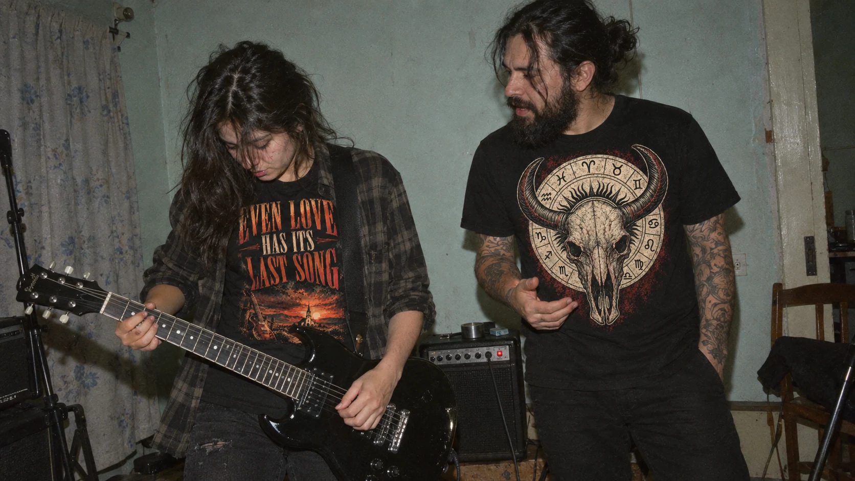 Dos amigos con las camisetas de Ritual Callejero en una habitación de ensayo, entre una guitarra y amplificadores